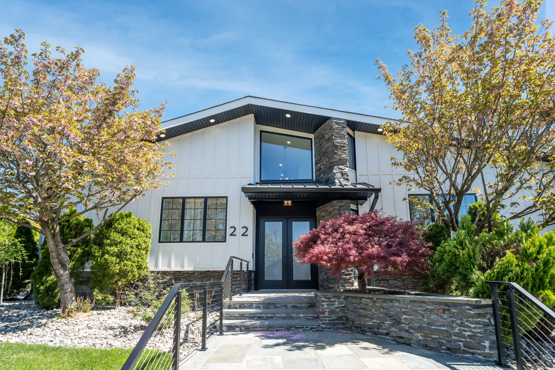 Englewood home front exterior after renovation — modern white facade with new stonework and landscaping
