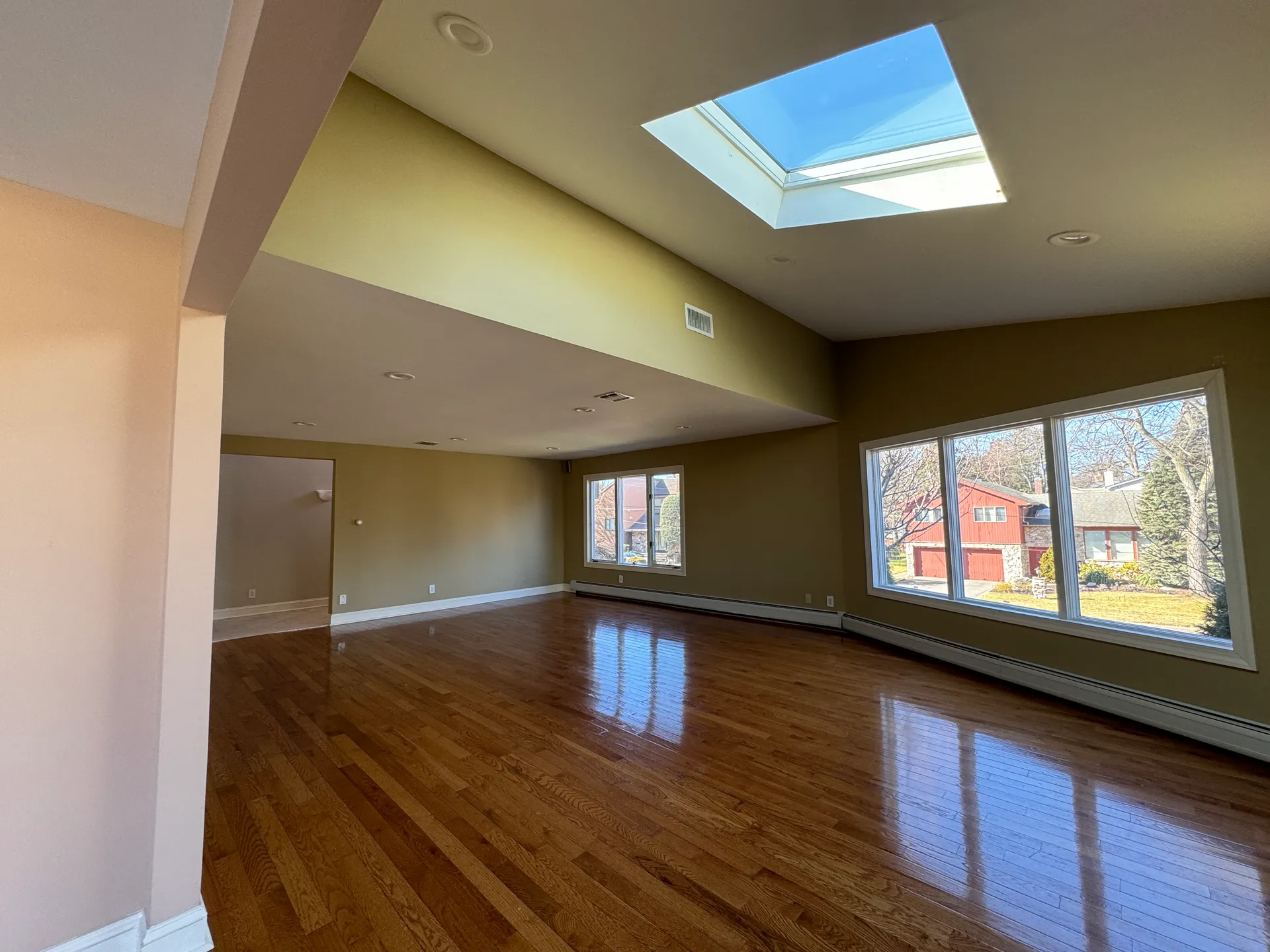 Empty great room with tan walls and dated flooring before renovation