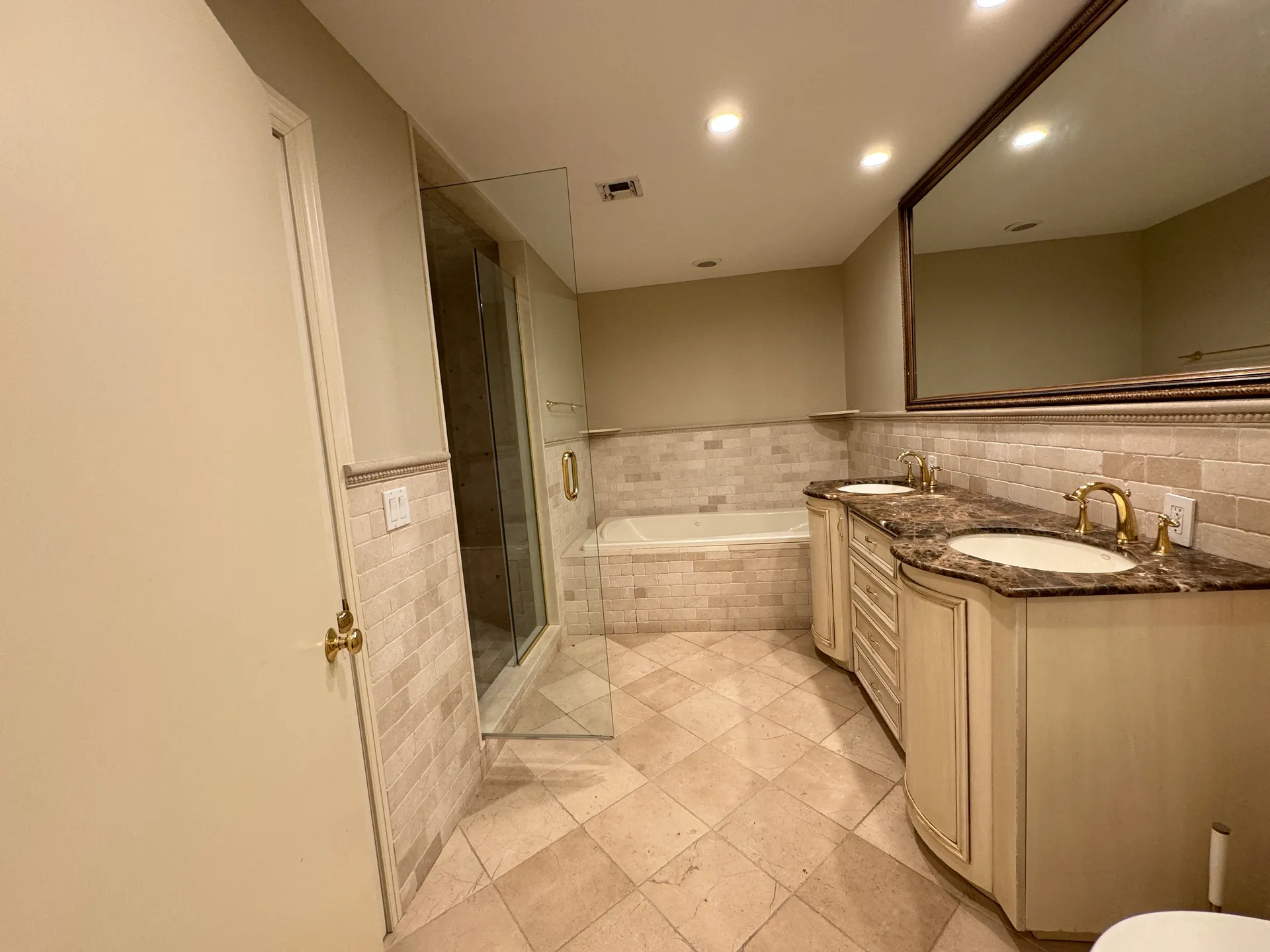 Dated primary bathroom with jacuzzi tub and travertine tile before renovation