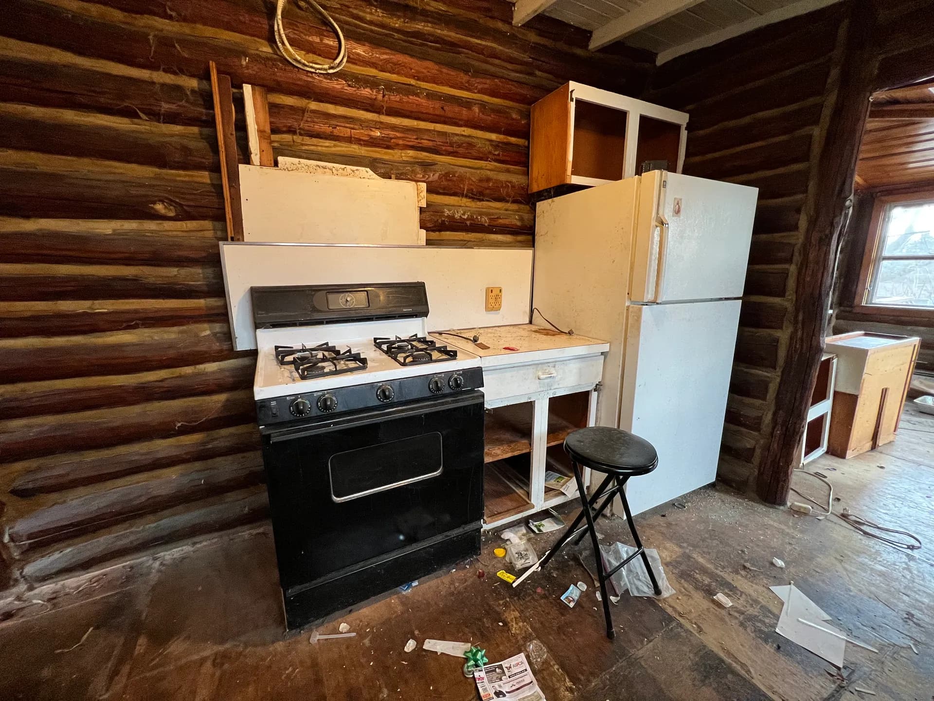 Original appliance corner before renovation — dated stove and fridge against the log wall