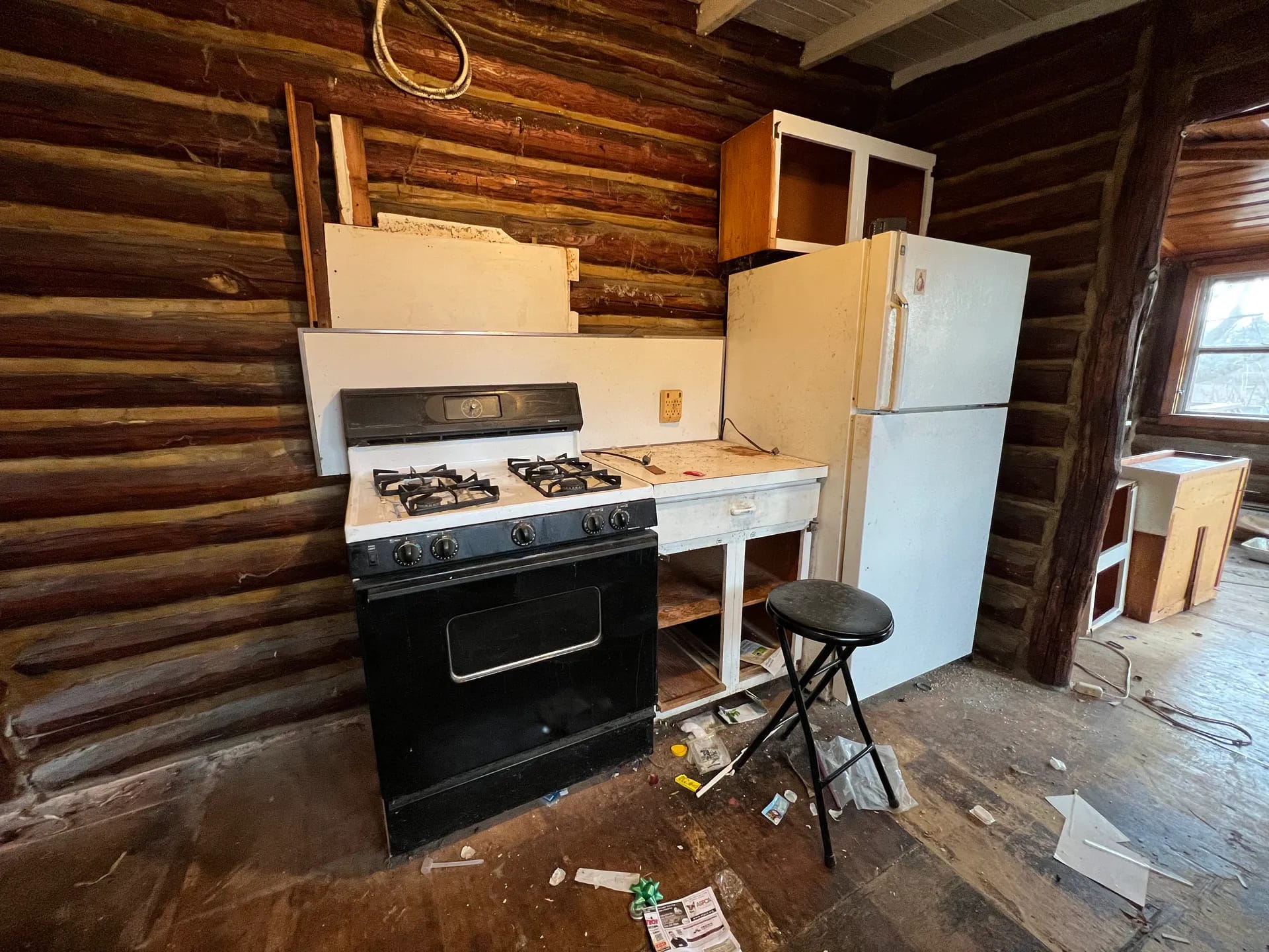 Original appliance corner before renovation — dated stove and fridge against the log wall