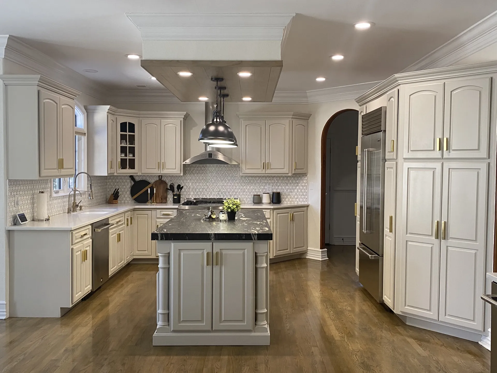 Renovation — Wyckoff, NJ — cream kitchen with black granite island, stainless hood, and wood ceiling panel