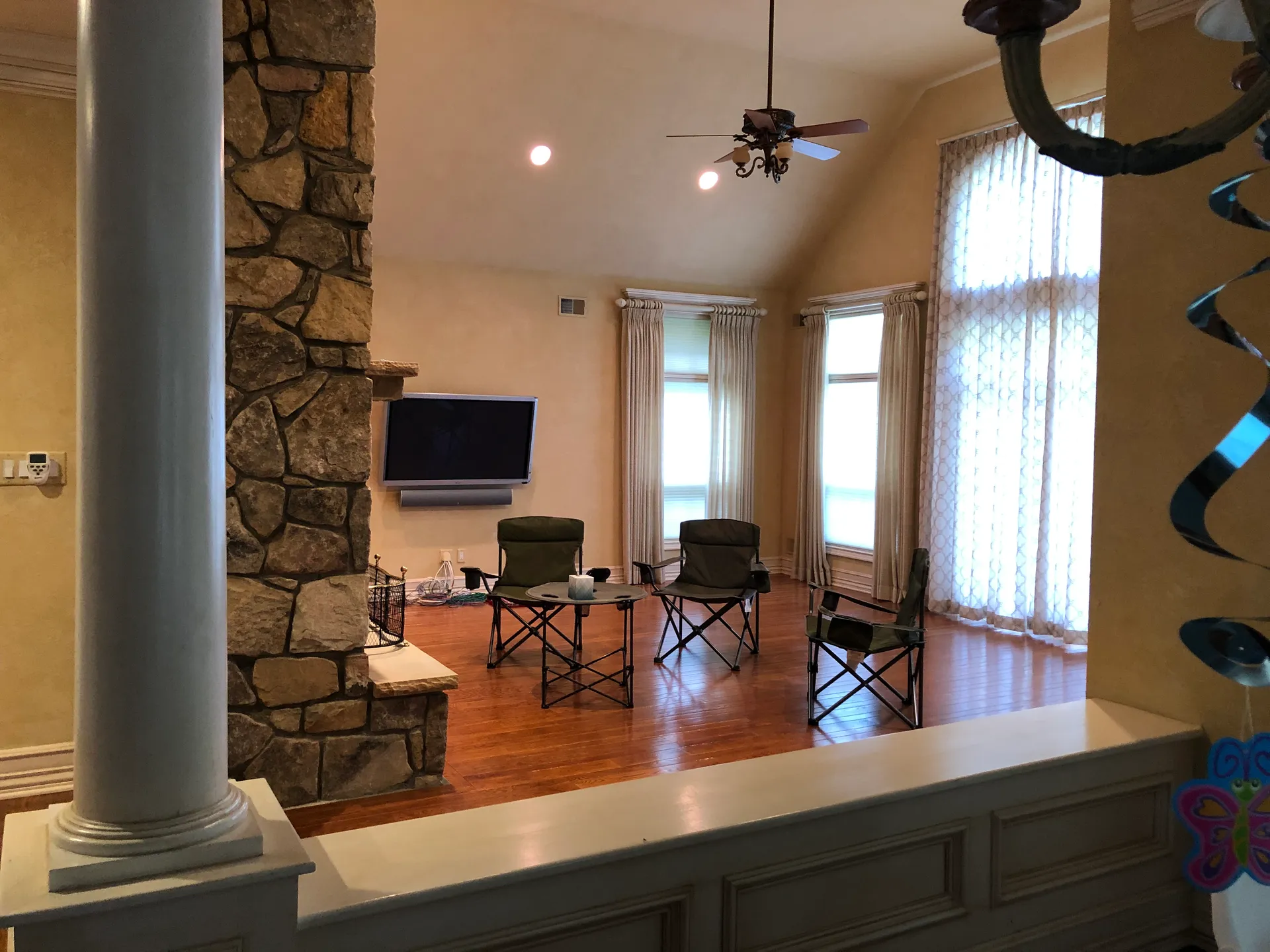Original great room with dated stone fireplace and yellow walls before renovation