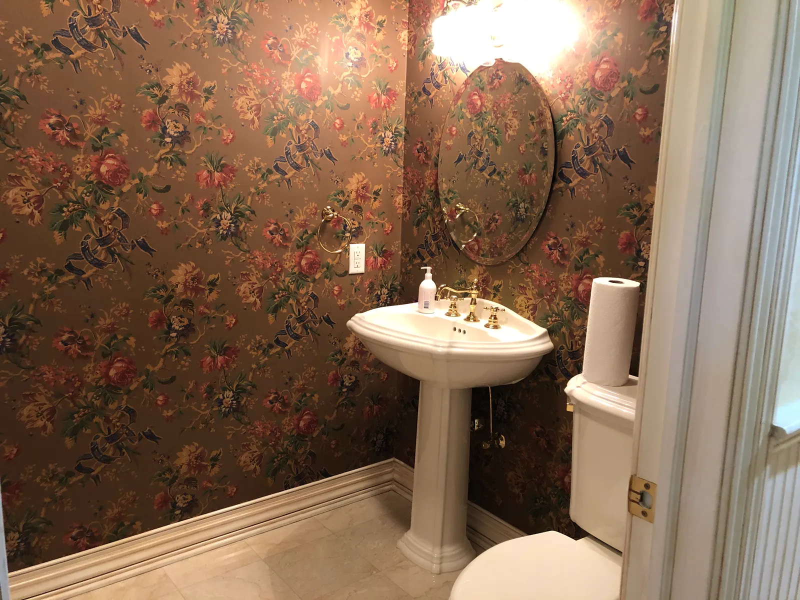 Bathroom before renovation — floral wallpaper and pedestal sink